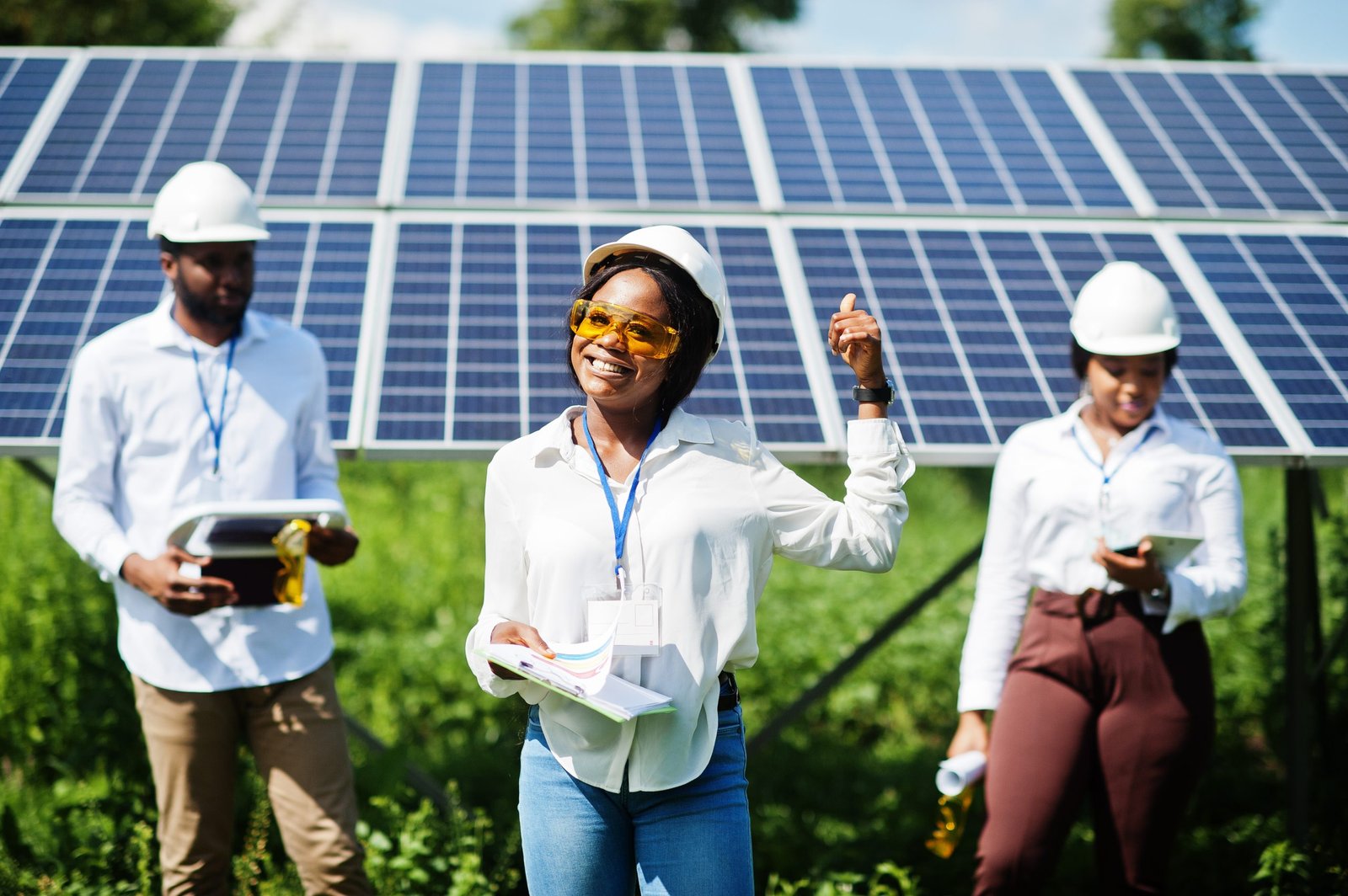 African american technician checks the maintenance of the solar panels. Group of three black engineers meeting at solar station.